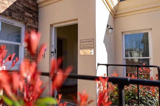 The reception entrance at Beechwood House, with the doorway marked Reception alongside flowering shrubs.